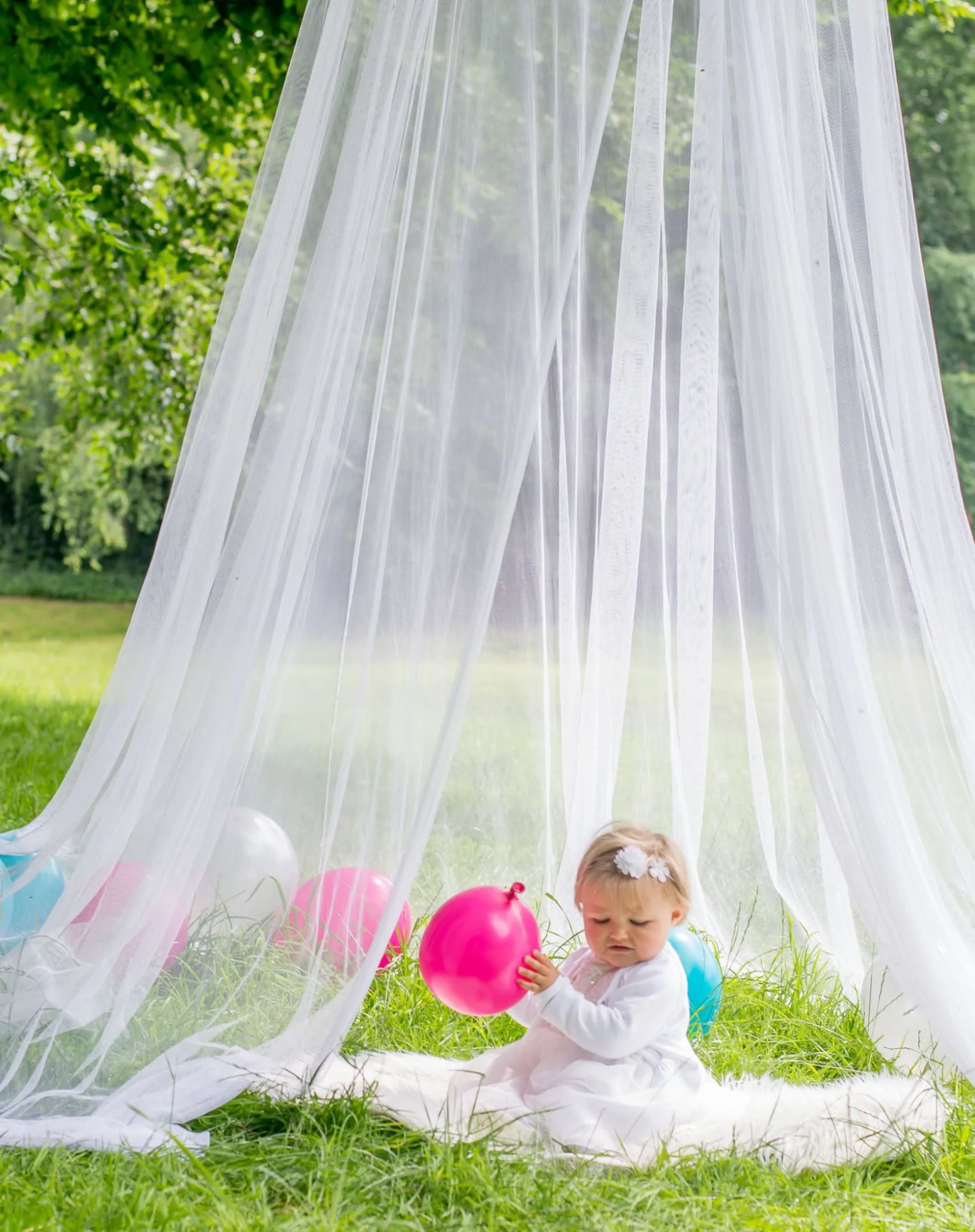 Petite fille avec un ballon sous un voile blanc